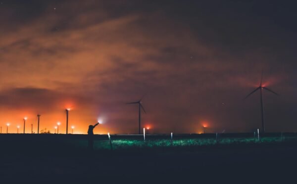 Photography of Person Holding Flashlight Near Windmills during Night Time